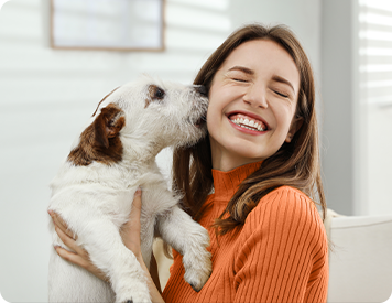Frau freut sich mit ihrem Hund über ihren Minikredit